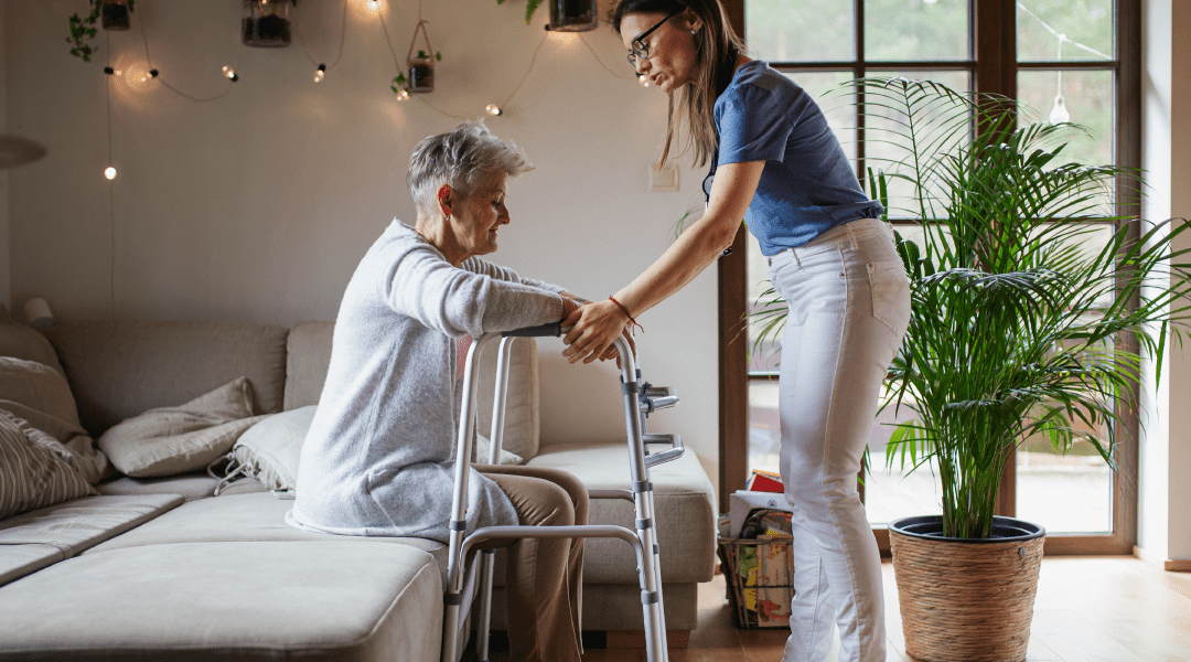 caregiver helping senior woman stand with walker