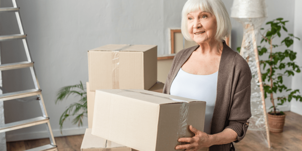 elderly woman holding a packed cardboard moving box