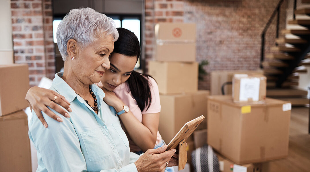 Shot of a senior woman looking at a photograph with her daughter with boxes in the background