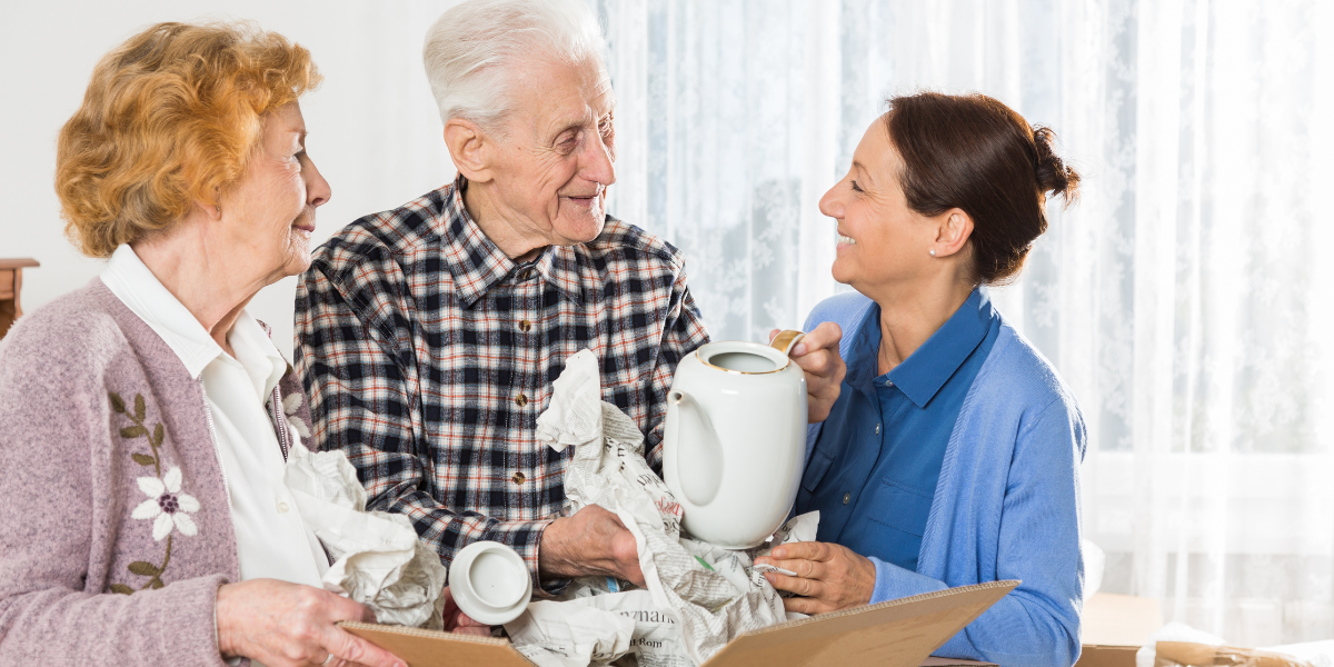 middle aged woman helping elderly couple with senior relocation moving process.